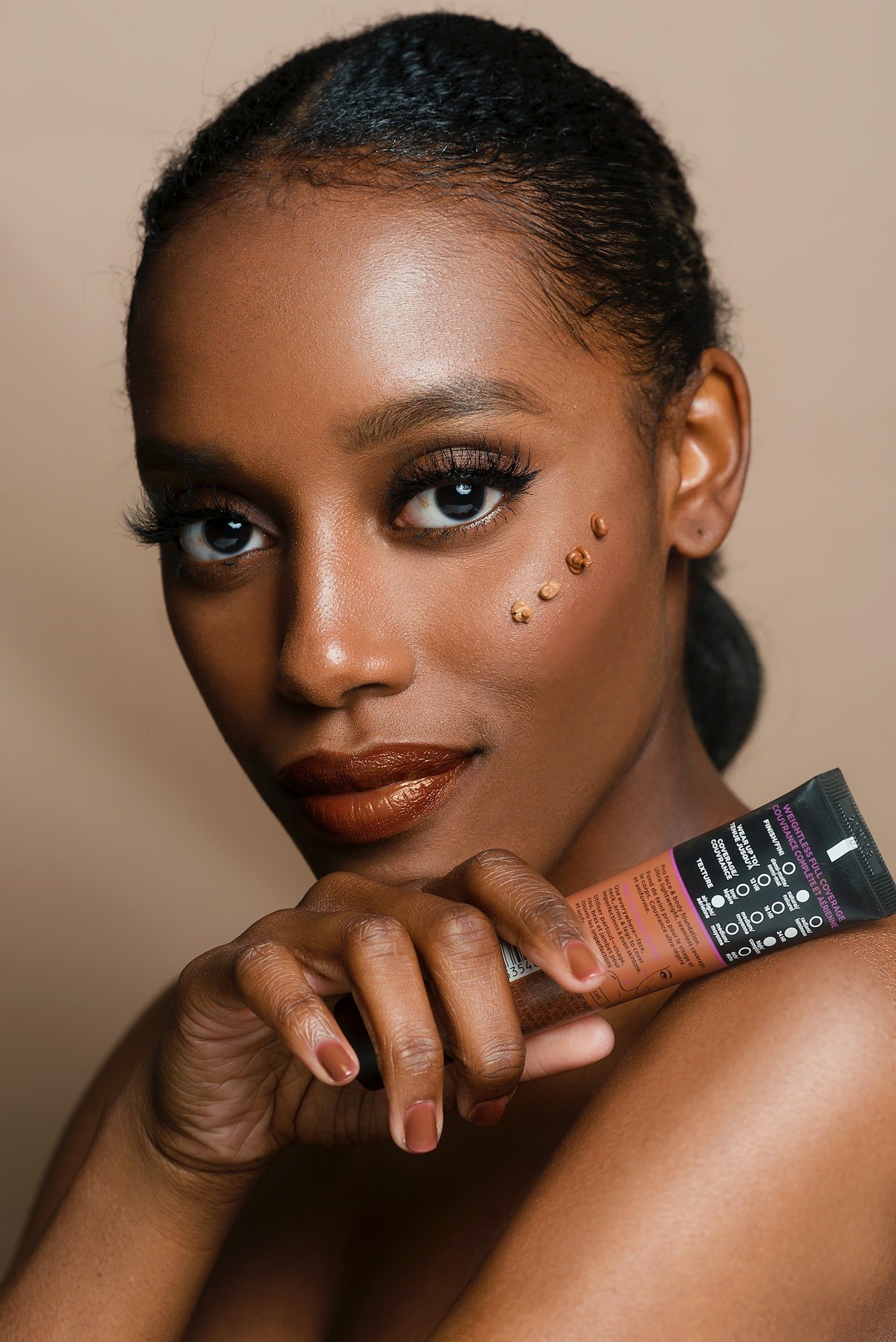 Woman holding a foundation, applying makup