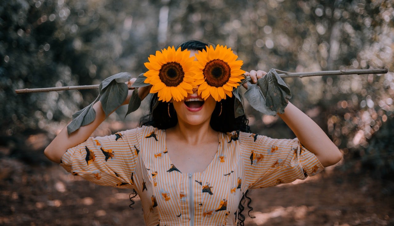 Woman covering her eyes with sunflowers
