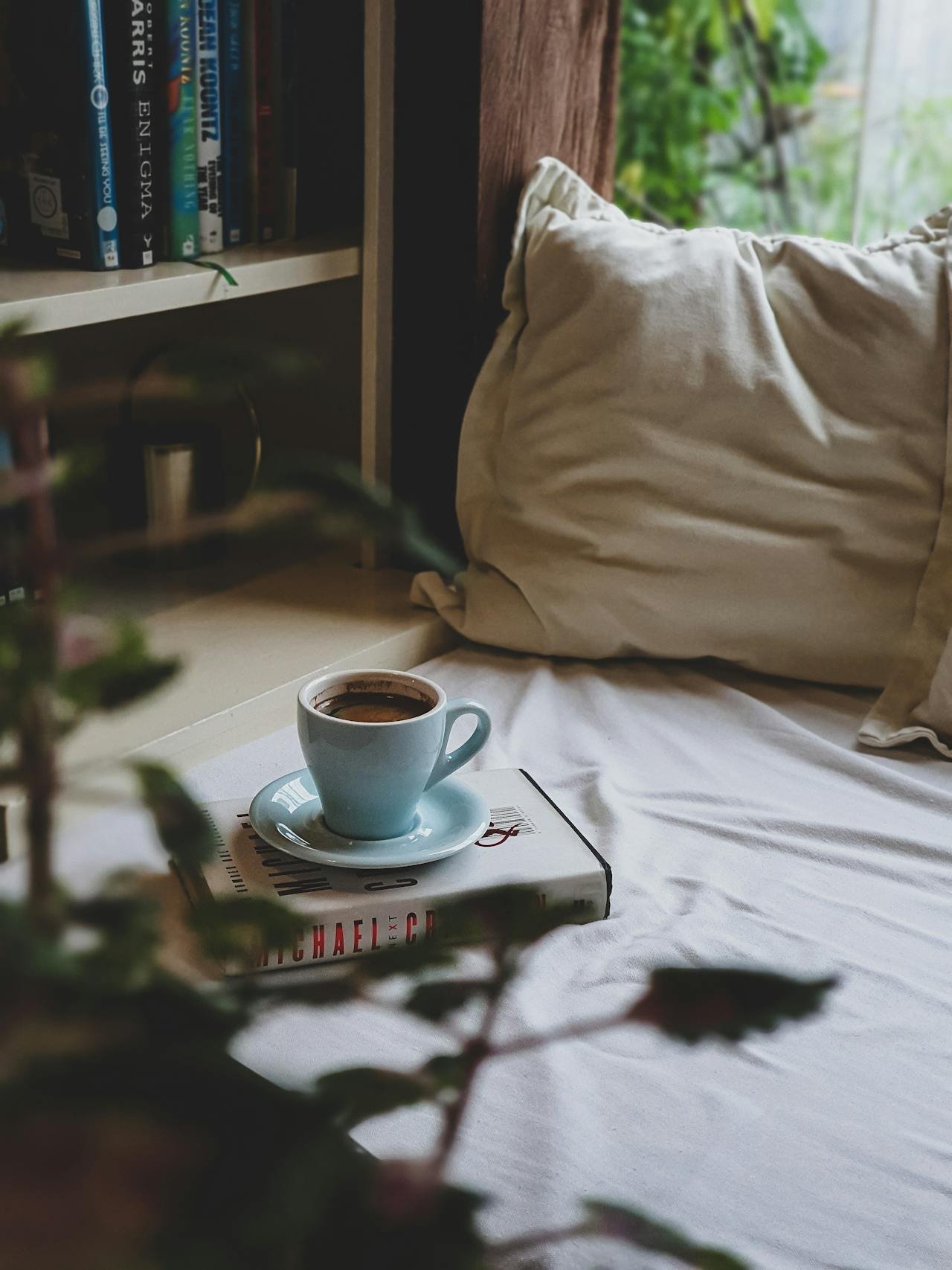 Blanket on the floor next to a floor cushion and bookshelf representing a reading nook or space