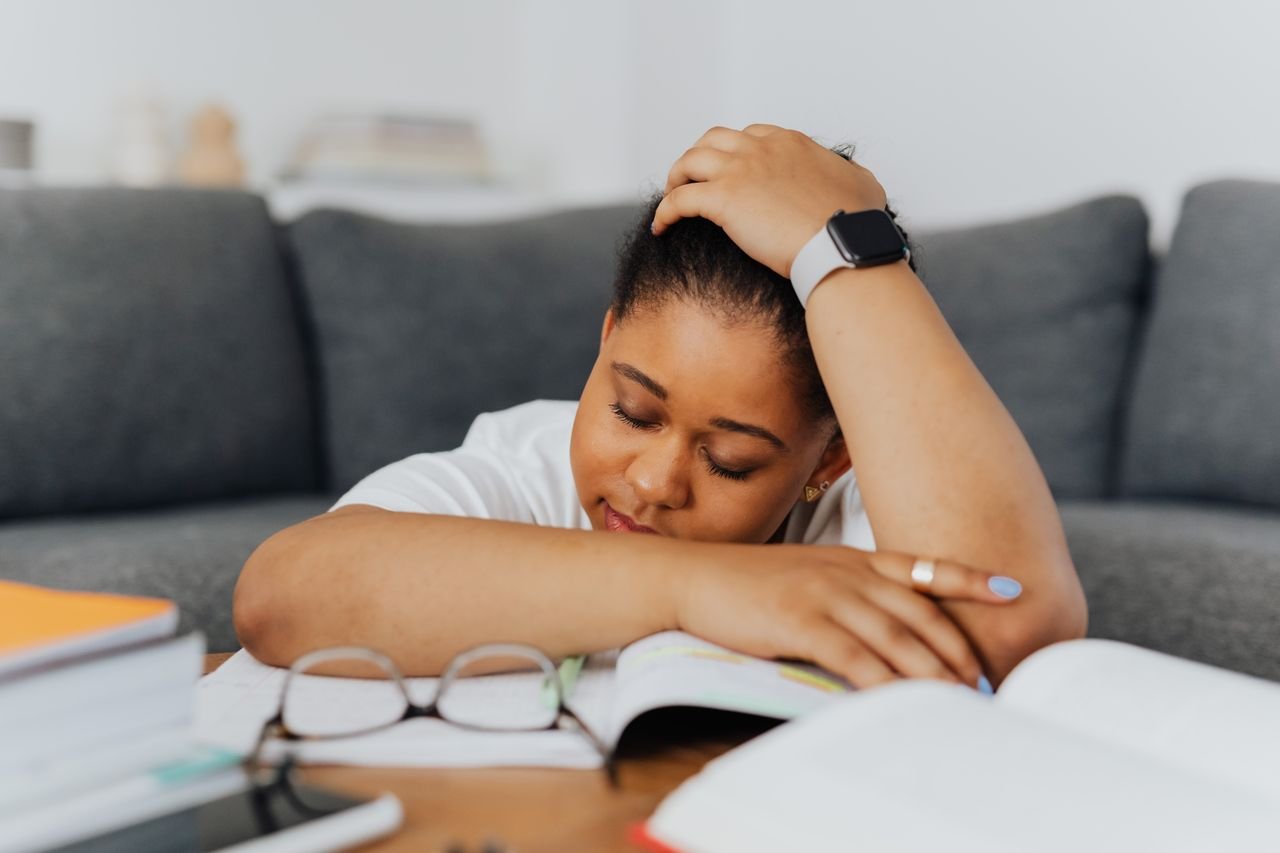 visibly tired woman leaning on study books