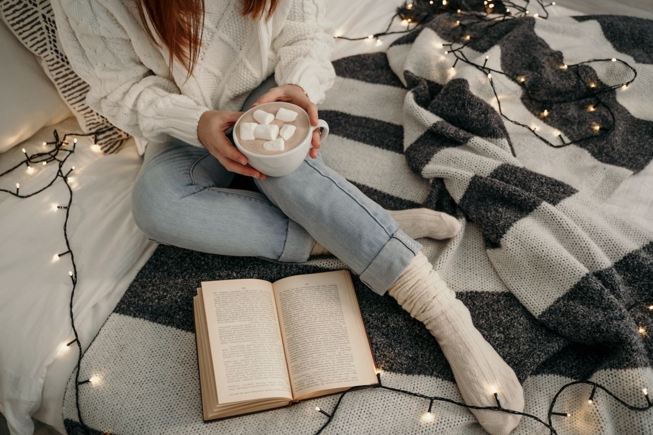 person sitting on bed surrounded by fairy lights
