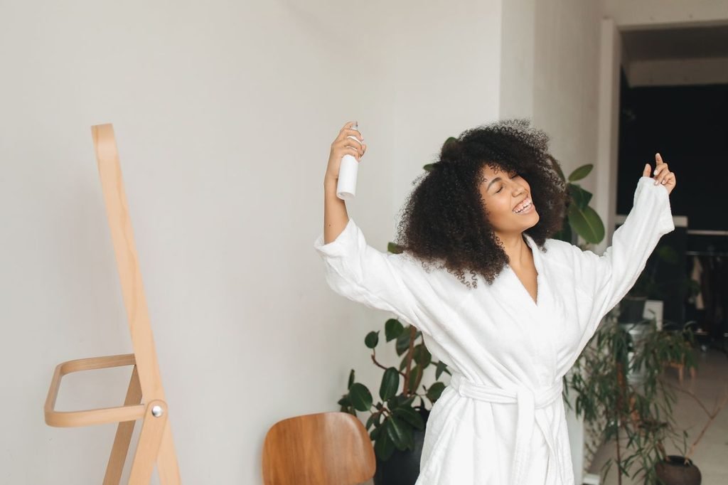 Woman in a white robe holding a hair product during a slow hair care routine